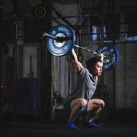 トレーニングジムでバーベルを頭上に掲げるスクワットスナッチの写真
