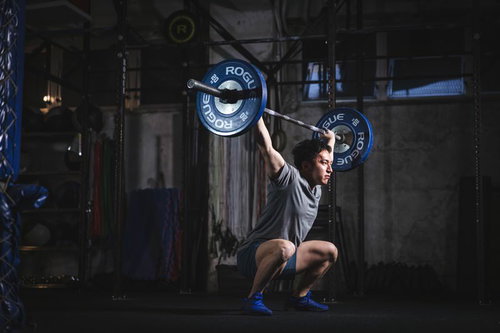 トレーニングジムでバーベルを頭上に掲げるスクワットスナッチ