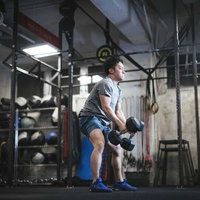 AMRAPトレーニングでダンベルのデビルプレスを行う男性アスリートの写真