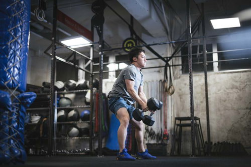 AMRAPトレーニングでダンベルのデビルプレスを行う男性アスリート