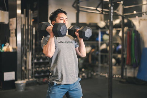 ジムでダンベルを使ったウエィトトレーニングを行う男性