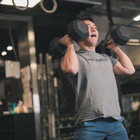 ジムでダンベルを使ったフィジカルトレーニングで筋力を鍛える男性の写真