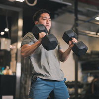 ジムでダンベルを使った筋トレを行う男性のトレーニング風景の写真