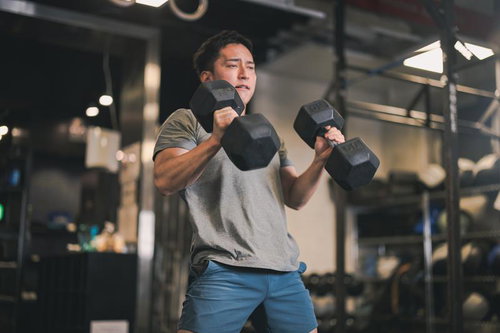 ジムでダンベルを使った筋トレを行う男性のトレーニング風景