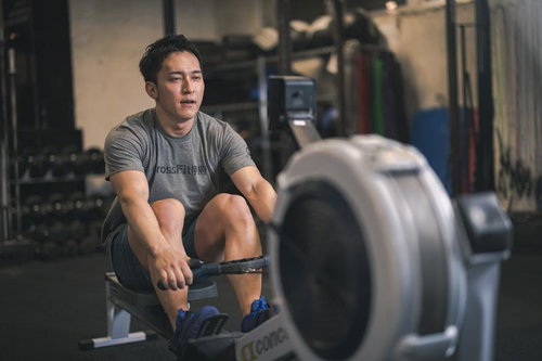 ローイングマシンで筋トレに取り組む男性のジムトレーニング