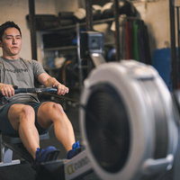 ローイングマシンで筋トレする男性のジムでのトレーニング風景の写真