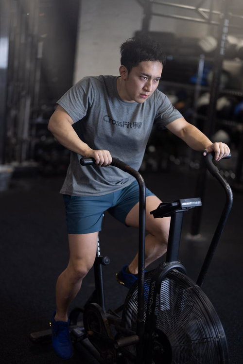 ジムでエアバイクを使用する男性のクロストレーナー