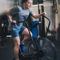 クロストレーナーで有酸素運動を行うジムの男性の写真