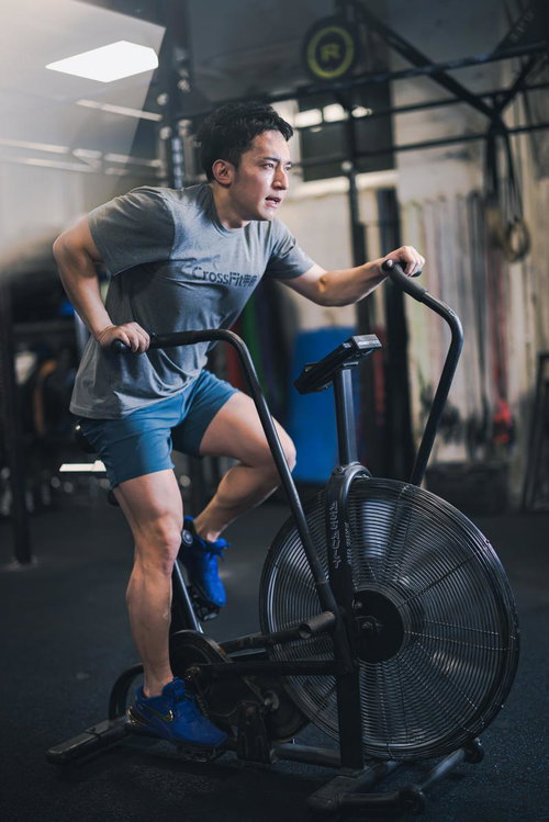 クロストレーナーで有酸素運動を行うジムの男性