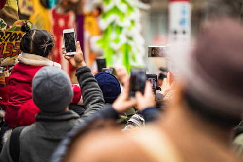 スマートフォンを取り出して撮影しはじめる人混みの風景