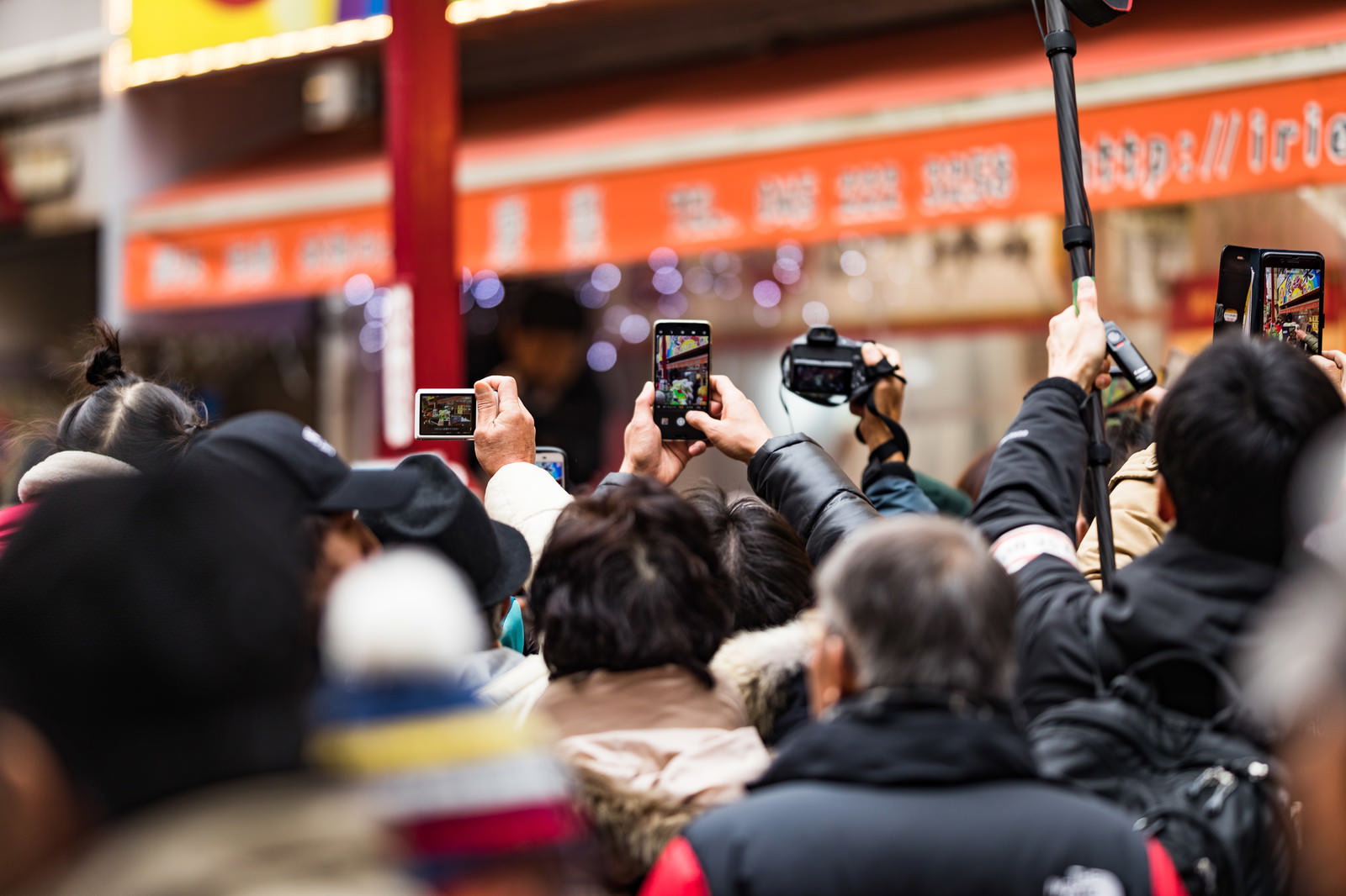 スマートフォンを構えて撮影している大勢の人たちの後ろ姿