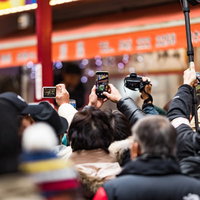 スマホで撮影する人たちの人だかりの写真