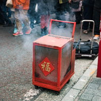 春節のイベントで爆竹が入れられた赤い箱から立ち上る白い煙の写真