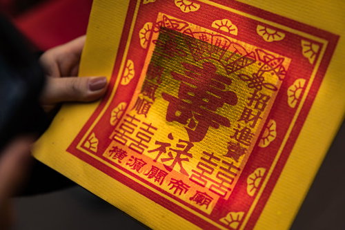 金紙を両手で持つ参拝者の手（横浜関帝廟）