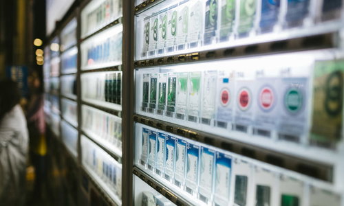 ガラスケースに並ぶ煙草の自動販売機の商品陳列風景