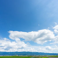 青空と白い雲が広がる福岡県大刀洗の平野と農村風景の写真