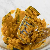 やわらかくなったカボチャをマッシャーで潰す調理シーンの写真