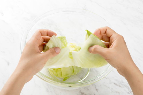 透明なボウルにレタスを一口サイズに手で千切る