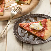 木製テーブルの皿に盛られたクリームチーズを乗せたカリフラワーピザの写真