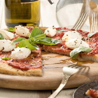 木製まな板に盛り付けたヘルシーなカリフラワーピザの写真