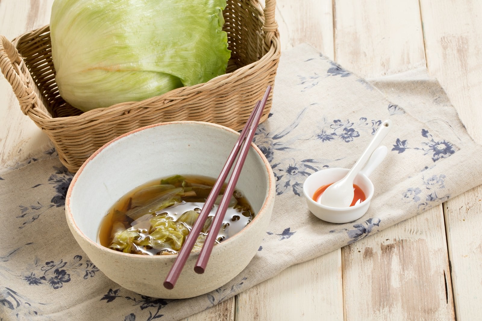 白いどんぶりに入ったレタスと野菜のスープと箸が置かれた食卓