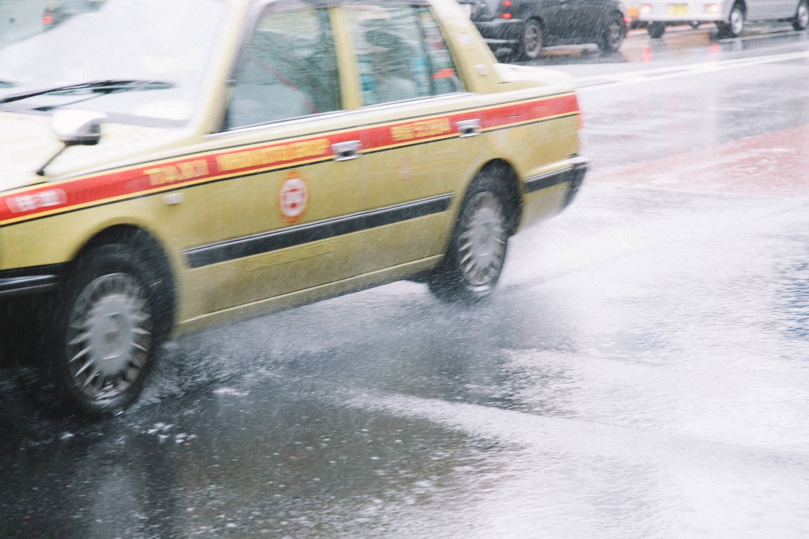 雨の中を走る黄色いタクシーの後ろ姿