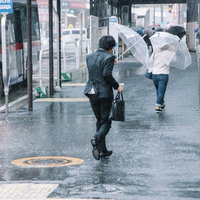 大雨と強風の中、出社する社畜ビジネスマン（びしょ濡れ）の写真