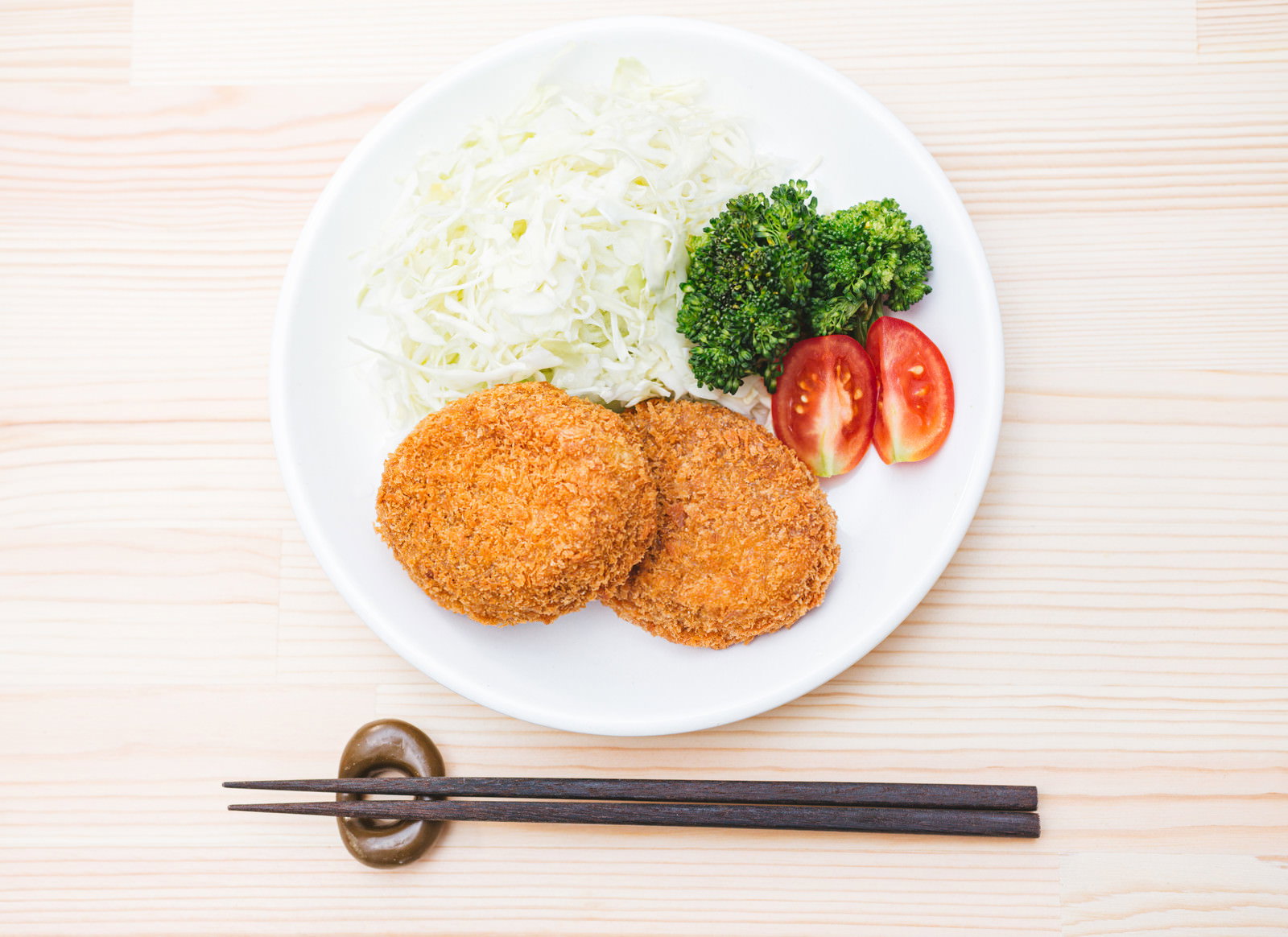 白い皿に盛られたコロッケ定食と箸
