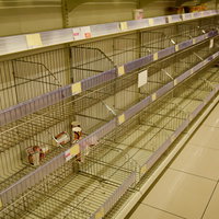 台風や災害時のスーパーの棚が品切れ状態になった売場の風景の写真