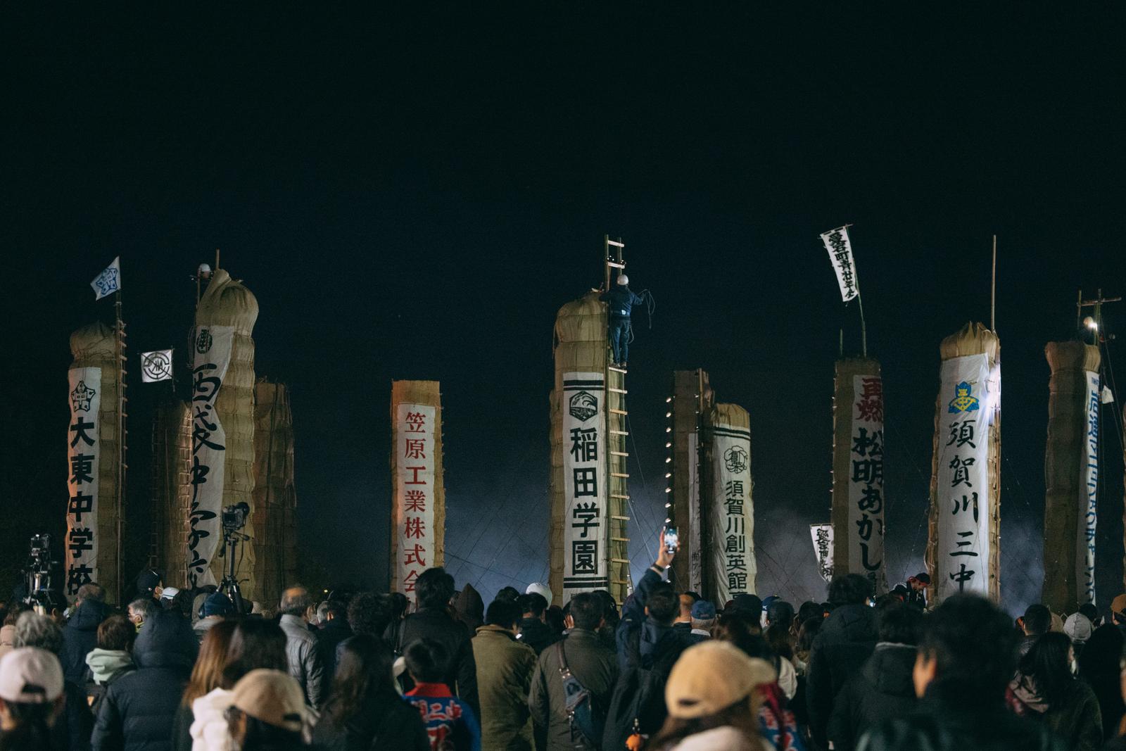 須賀川市の五老山山頂で松明あかしが行われ、観衆が集まる夜間の光景