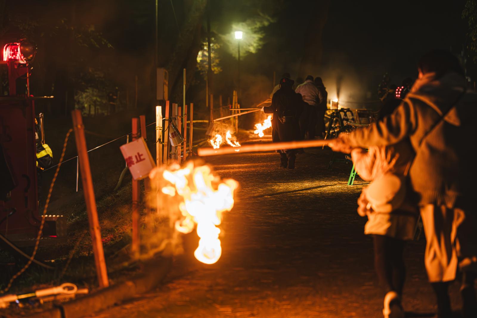 夜の通路で炎を奉納する小松明行列の参加者たちと火の玉