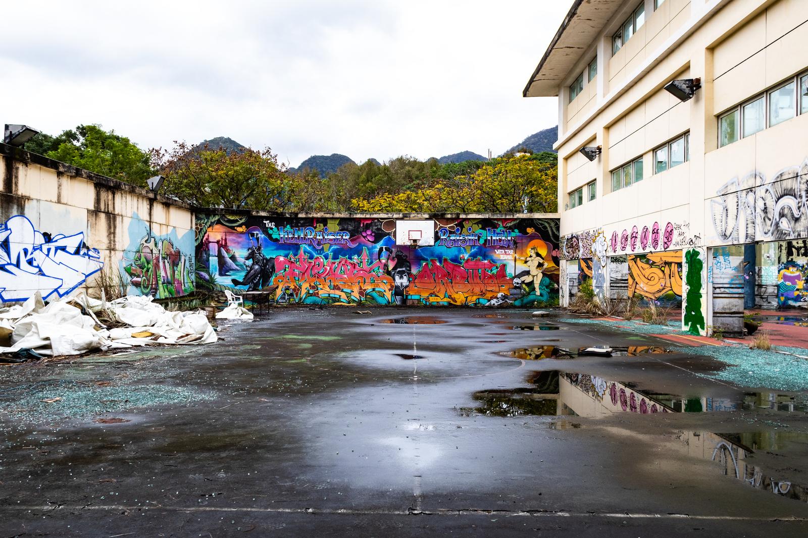 Colorful graffiti and basketball goal depicted on an abandoned plaza after rain