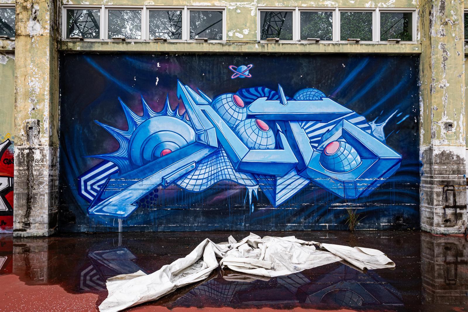 Blue 3D lettering graffiti art drawn on the exterior wall of an old building