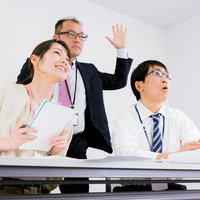 会議中に挙手して意見を述べる男性社員とビジネスマンのミーティングの写真