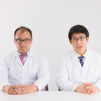 硬い表情で向き合う白衣の医師と研究員による記者会見の写真