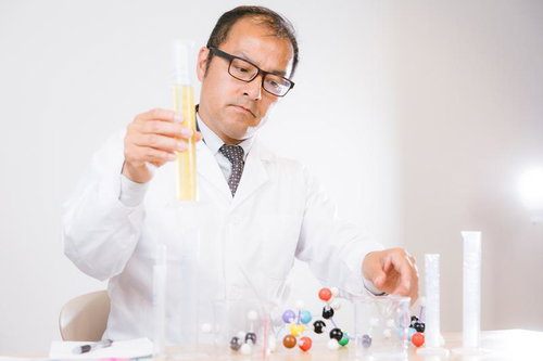 試験管を観察する白衣着用の男性研究員、化学実験室での研究風景