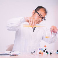 液体を調合する白衣着用の男性研究員が試験管で実験する科学の写真