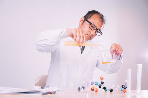 液体を調合する白衣着用の男性研究員が試験管で実験する科学