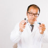 分子構造のモデルを手に持つ眼鏡をかけた白衣の科学者の写真
