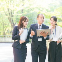 屋外でタブレットを使いながらジョブトレーニングする上司と部下の写真