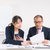書類を確認しながら意見交換する男女社員の打ち合わせの写真