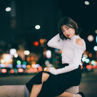 夜の繁華街でネオンに包まれて一息つく女性の写真