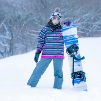 スキー場のゲレンデで佇むスノーボーダー女性の写真