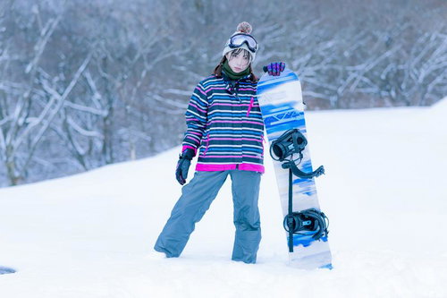 スキー場のゲレンデで佇むスノーボーダー女性