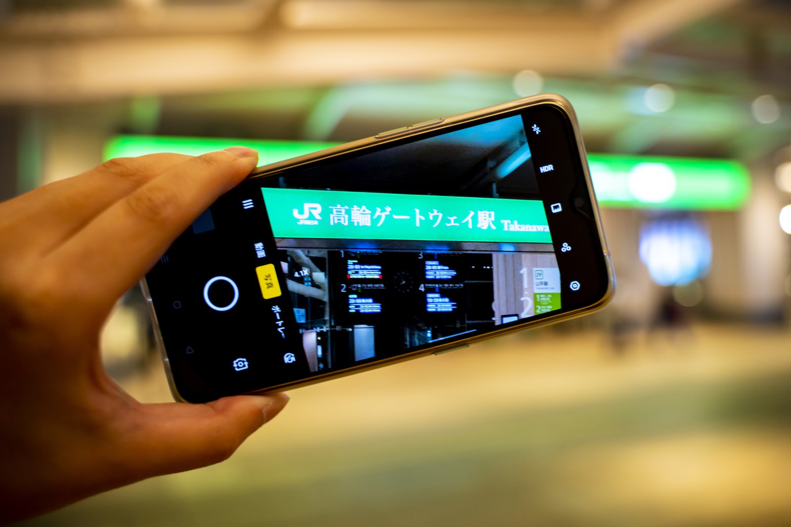 スマートフォンで高輪ゲートウェイ駅の改札を撮影している様子