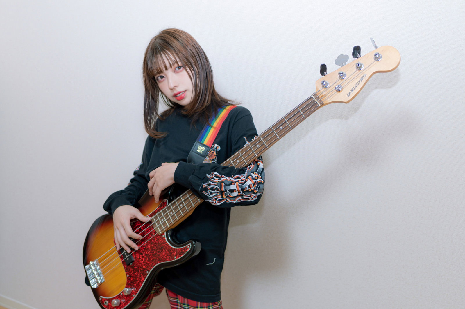 黒いエレキベースを抱えて立つ女性［モデル：高尾実生］