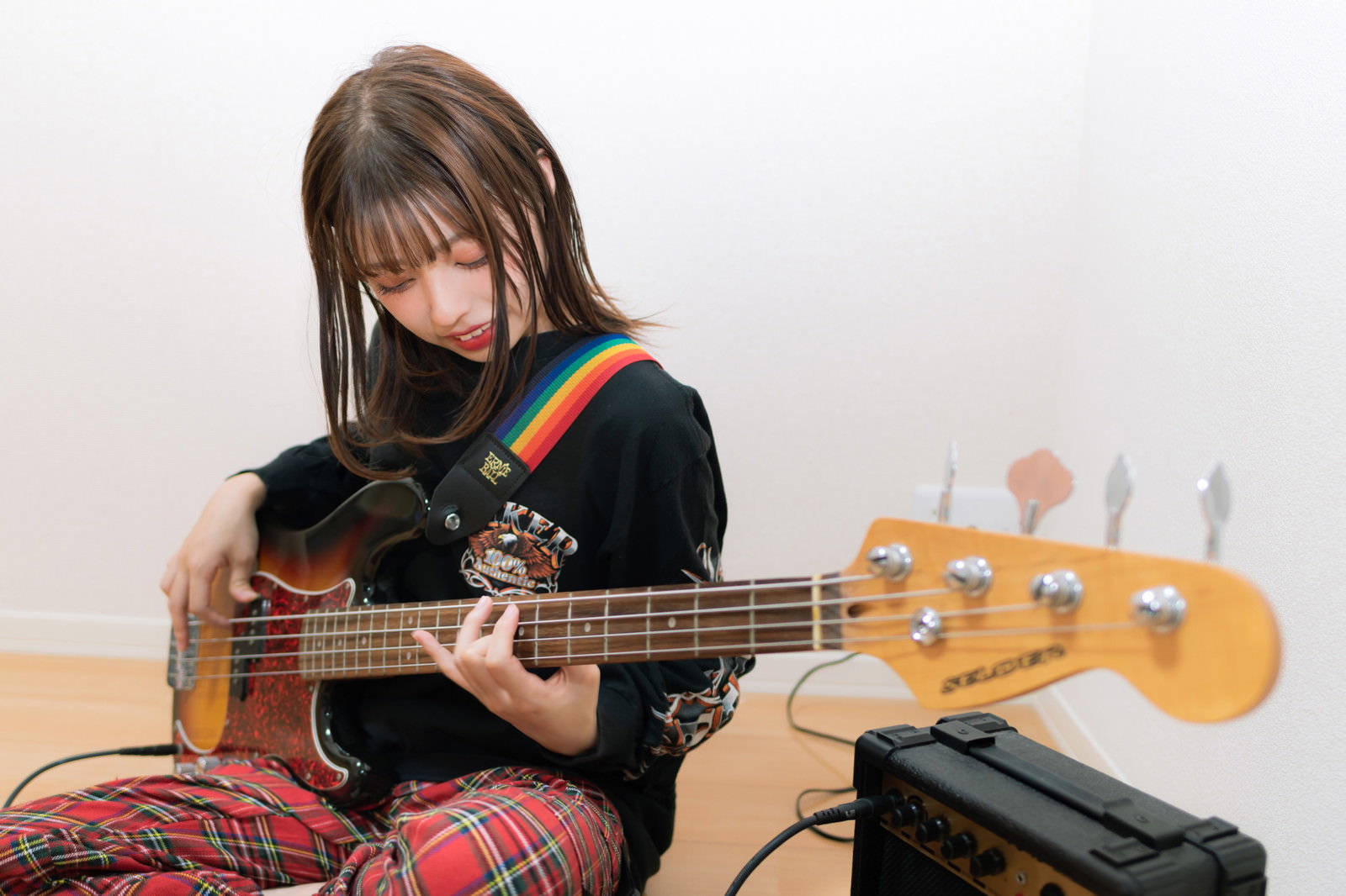 黒いトップスを着た女性がベースを指弾きで演奏している様子［モデル：高尾実生］