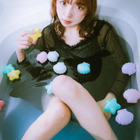 浴槽に浸かるカラフルなバスボムに囲まれた女子の写真