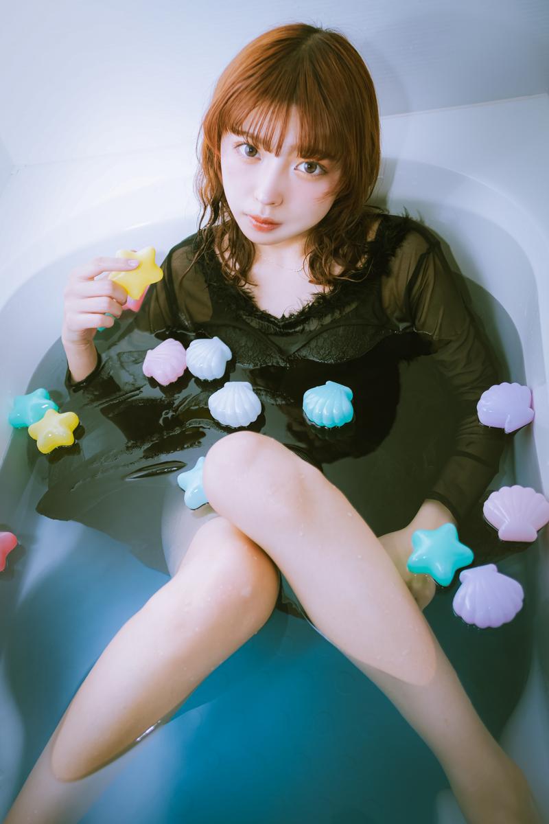 カラフルなバスボムが浮かぶ浴槽に浸かる女性［モデル：高尾実生］