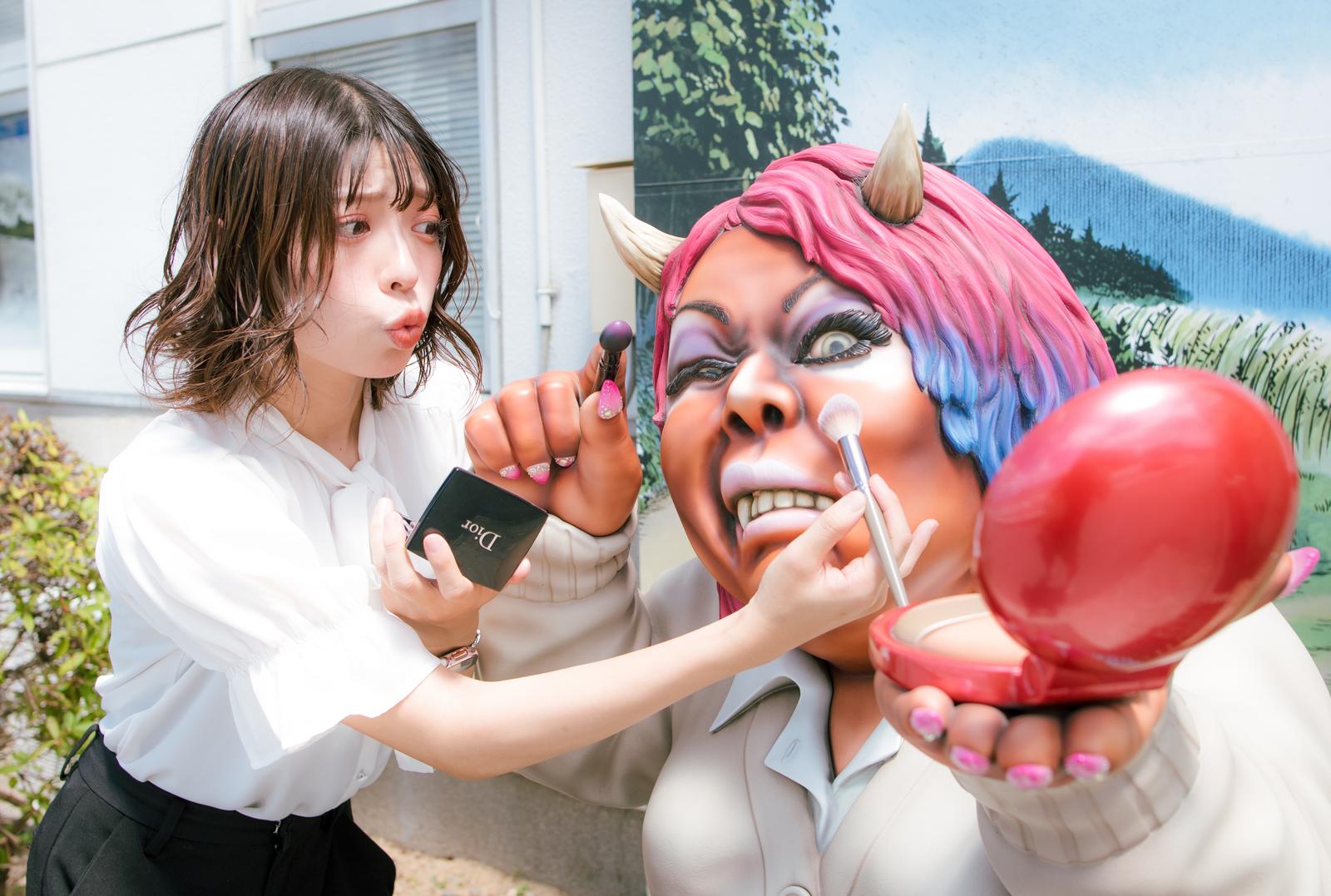 ギャルメイク中の山姥にメイクブラシで化粧を施す女性［モデル：高尾実生］